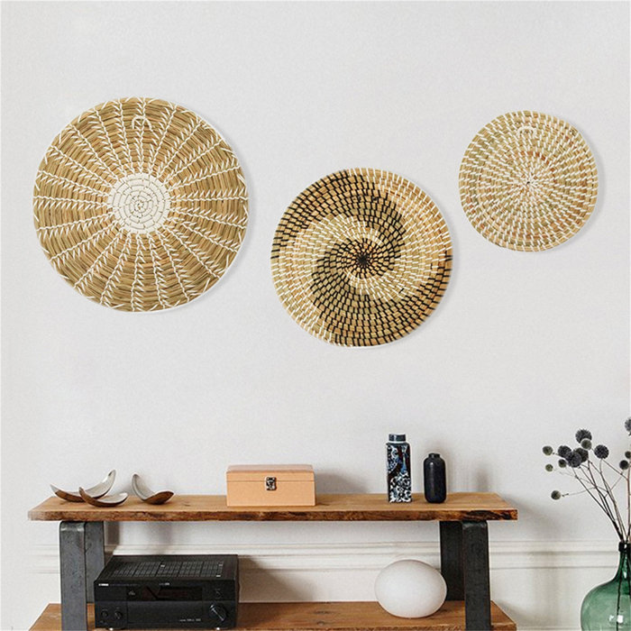 A set of three coordinated woven baskets arranged artistically on a wall.